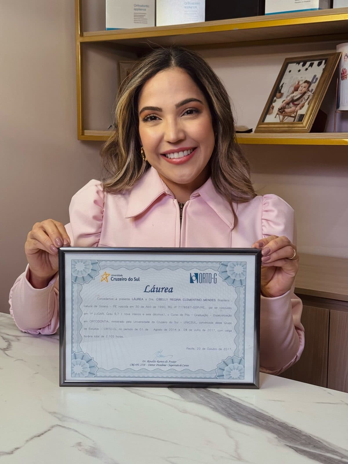 Dra. Cibelly Mendes segurando seu certificado de láurea